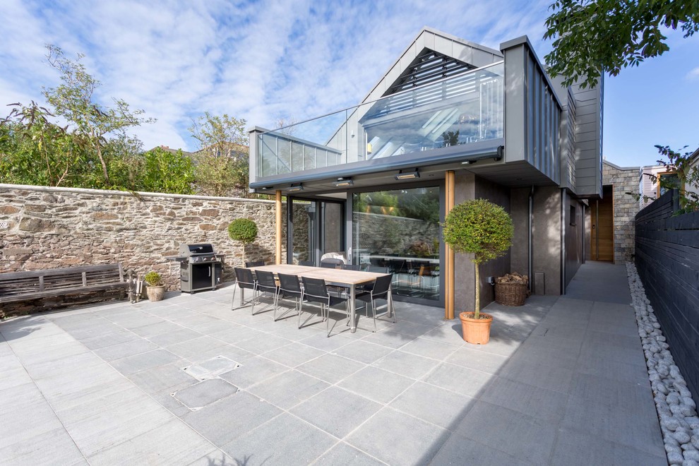 Large contemporary backyard patio in Devon with an outdoor kitchen, natural stone pavers and a roof extension.