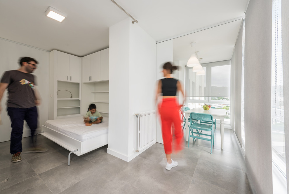 This is an example of a mid-sized contemporary gender-neutral kids' bedroom for kids 4-10 years old in Madrid with white walls.