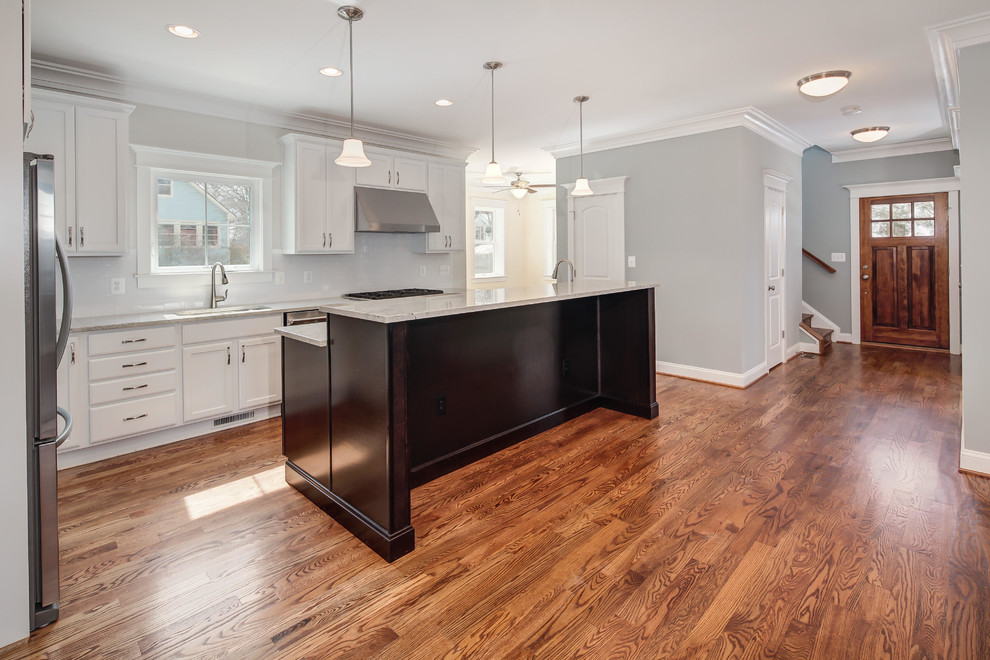 Photo of a transitional l-shaped kitchen in DC Metro with an undermount sink, white cabinets, granite benchtops, stainless steel appliances, medium hardwood floors and with island.