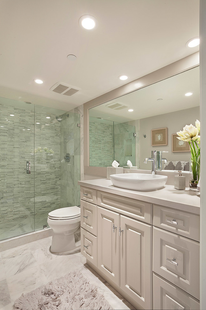 Example of a mid-sized transitional 3/4 gray tile and glass tile marble floor and multicolored floor alcove shower design in Miami with multicolored walls, recessed-panel cabinets, beige cabinets, a two-piece toilet, a vessel sink, solid surface countertops, a hinged shower door and white countertops