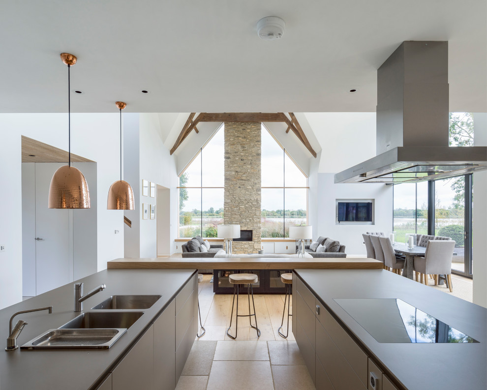 Design ideas for a large country u-shaped open plan kitchen in Wiltshire with flat-panel cabinets, beige cabinets, laminate benchtops, stainless steel appliances, limestone floors, grey benchtop, an integrated sink and beige floor.