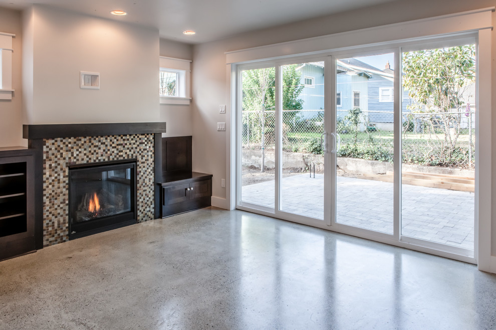 Inspiration for a small transitional open concept living room in Portland with white walls, concrete floors, a standard fireplace, a tile fireplace surround and a wall-mounted tv.