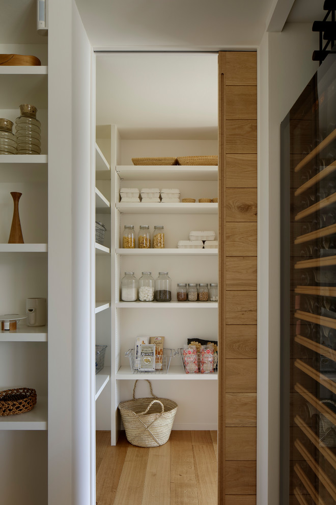 Inspiration for a scandinavian kitchen pantry in Other with open cabinets, white cabinets, medium hardwood floors and brown floor.