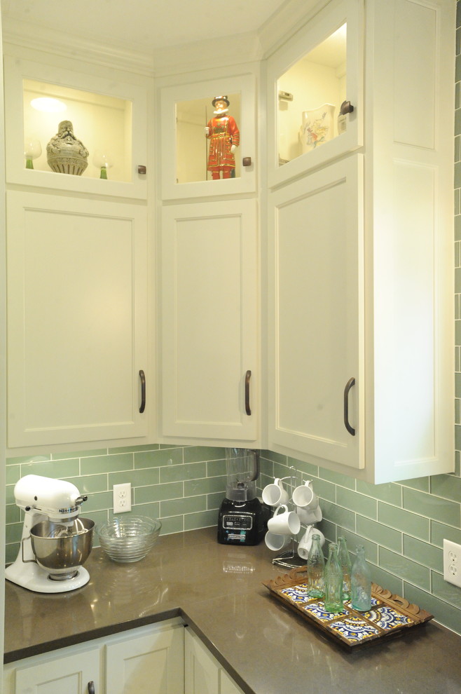 Example of a transitional u-shaped travertine floor kitchen design in Atlanta with a single-bowl sink, recessed-panel cabinets, white cabinets, quartz countertops, green backsplash, glass tile backsplash, stainless steel appliances and an island