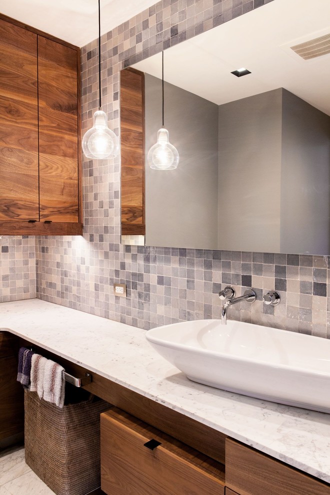 Design ideas for a mid-sized midcentury master bathroom in New York with flat-panel cabinets, dark wood cabinets, gray tile, stone tile, grey walls, marble floors, a vessel sink, marble benchtops, white floor and a drop-in tub.