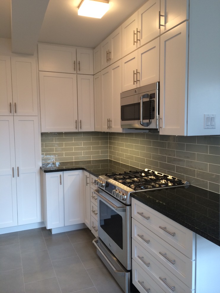 Example of a mid-sized transitional u-shaped porcelain tile enclosed kitchen design in Orange County with an undermount sink, shaker cabinets, white cabinets, granite countertops, gray backsplash, ceramic backsplash, stainless steel appliances and no island