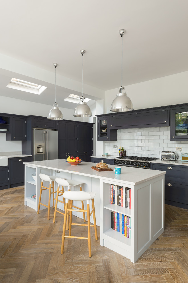 Mid-sized traditional eat-in kitchen in London with shaker cabinets, dark wood cabinets, quartzite benchtops, with island, white splashback, subway tile splashback, stainless steel appliances, medium hardwood floors and brown floor.