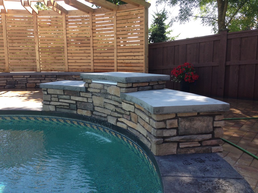 Mid-sized transitional backyard brick and custom-shaped lap pool fountain photo in Vancouver