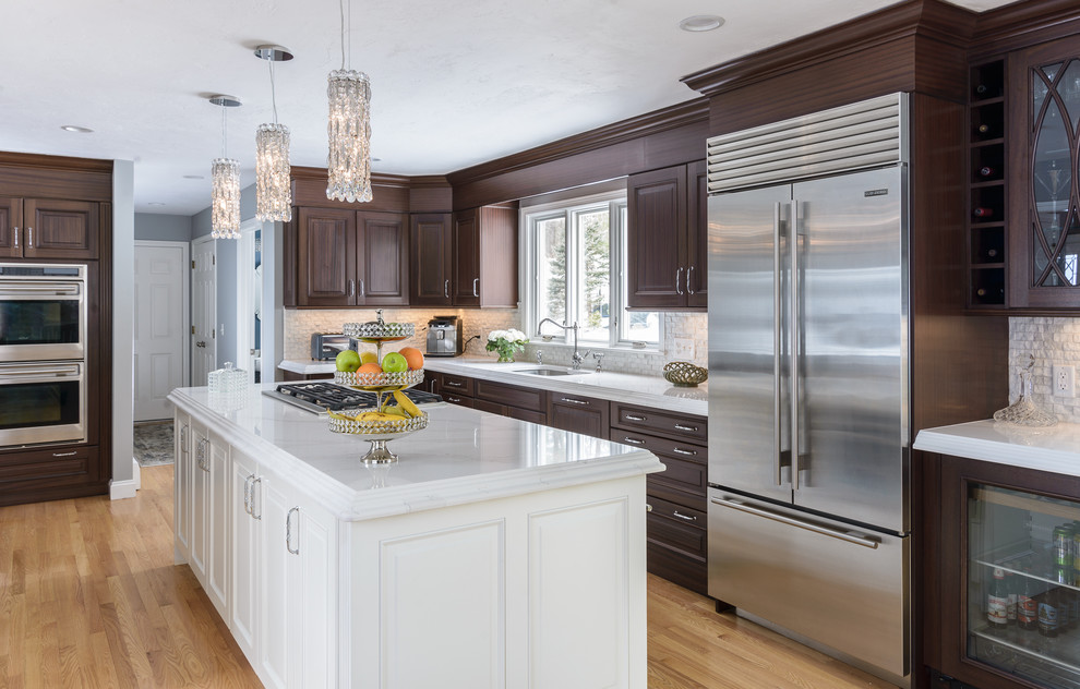 Large traditional l-shaped kitchen in Boston with an undermount sink, raised-panel cabinets, dark wood cabinets, quartzite benchtops, stainless steel appliances, light hardwood floors and with island.