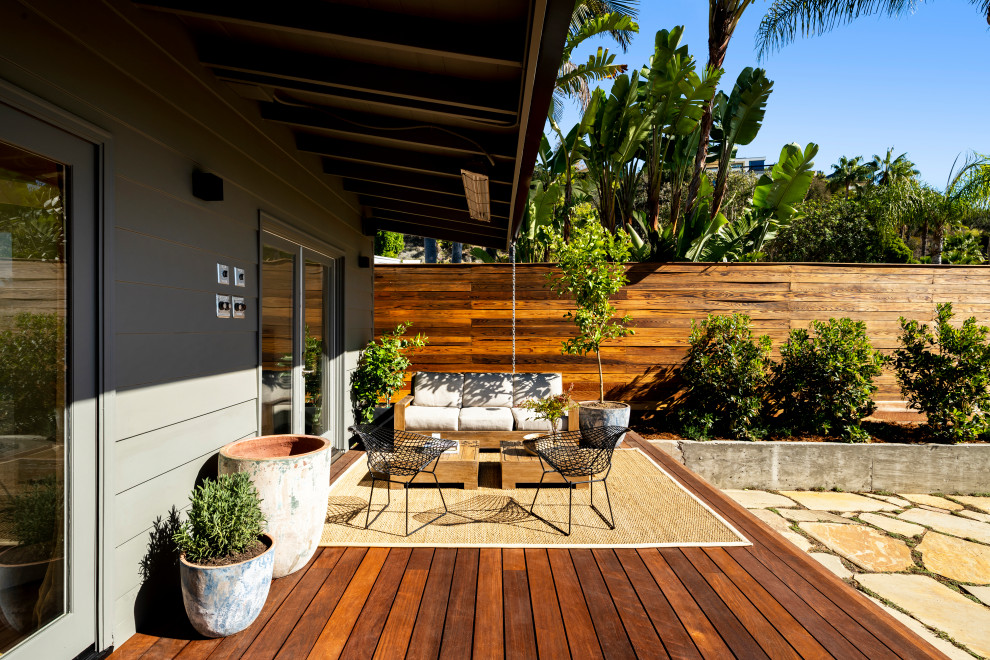 Idéer för en mellanstor eklektisk terrass på baksidan av huset, med takförlängning och räcke i trä