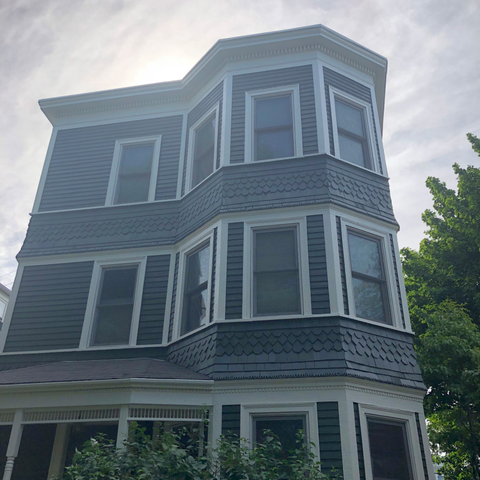 Photo of a large traditional three-storey black house exterior in Boston with wood siding, a flat roof and a shingle roof.
