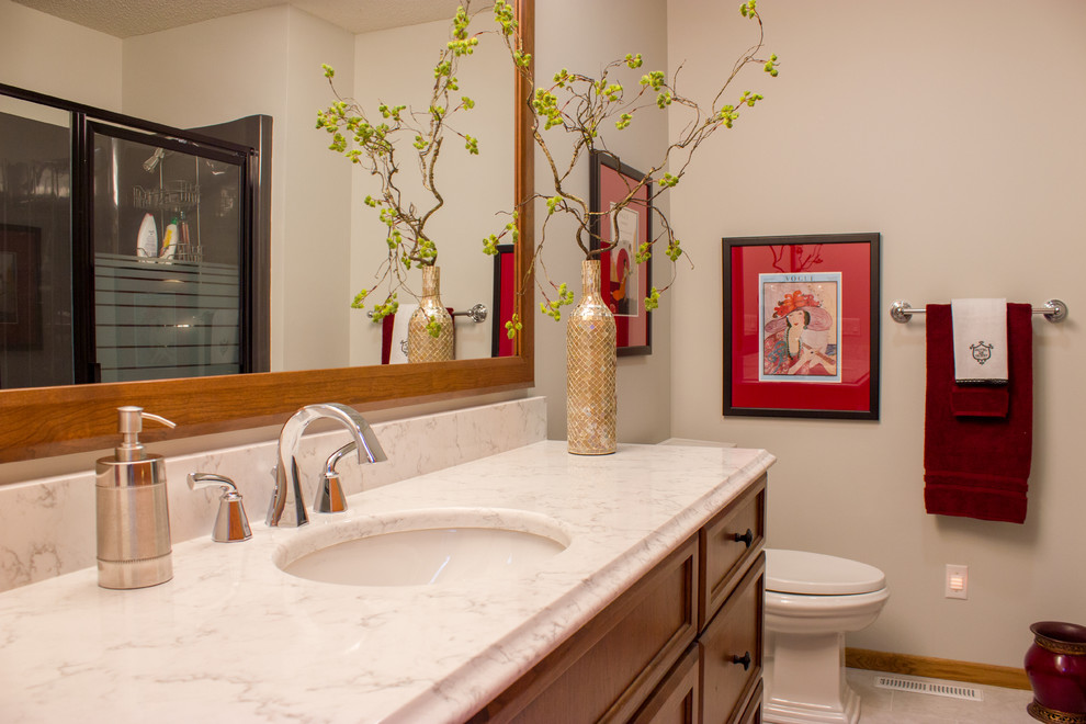 Example of a large transitional single-sink bathroom design in Cedar Rapids with recessed-panel cabinets, medium tone wood cabinets, quartz countertops, beige walls, a built-in vanity, a one-piece toilet and a drop-in sink