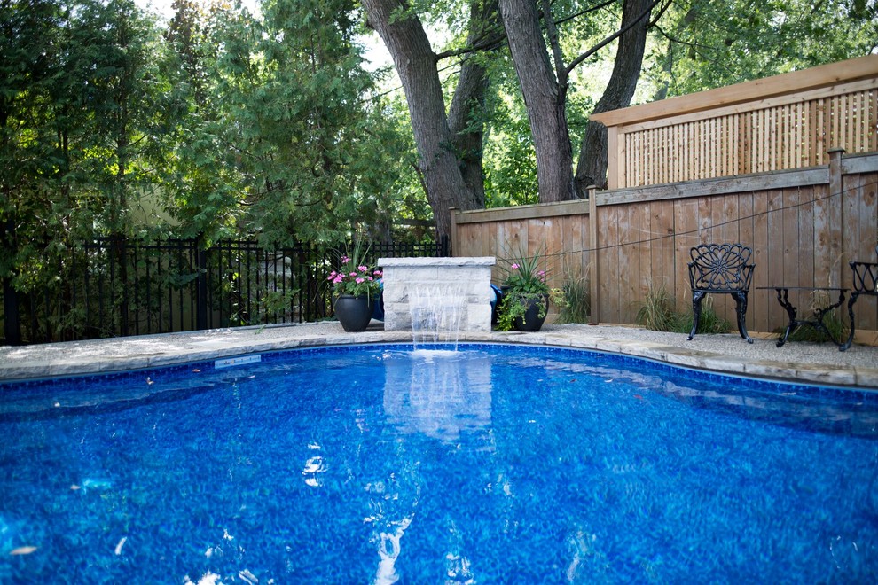 This is an example of a mid-sized traditional backyard custom-shaped pool in Toronto with a water feature and concrete slab.
