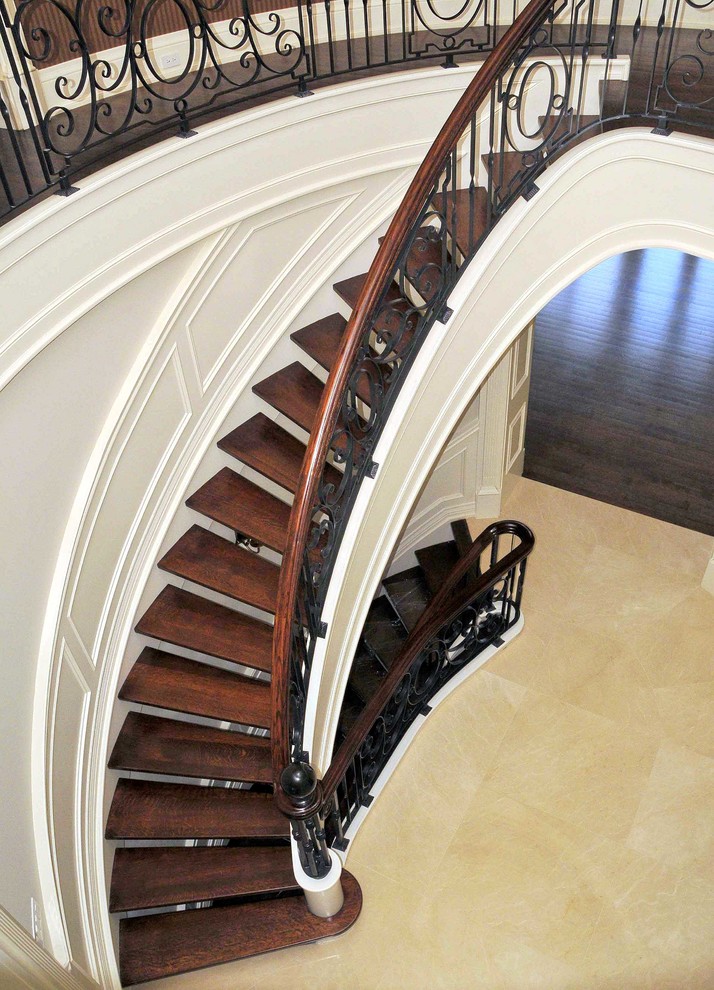 Large mediterranean wood curved staircase in Toronto with open risers.