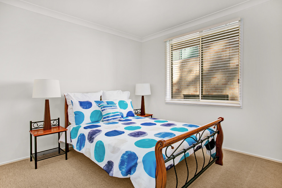 Photo of a mid-sized beach style guest bedroom in Newcastle - Maitland with white walls, carpet, no fireplace and brown floor.