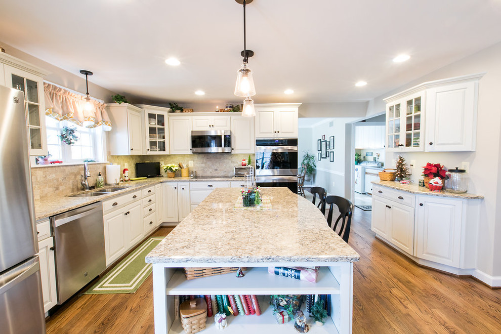 Mid-sized traditional l-shaped eat-in kitchen in Baltimore with an undermount sink, raised-panel cabinets, white cabinets, quartz benchtops, beige splashback, stone tile splashback, stainless steel appliances, medium hardwood floors and with island.