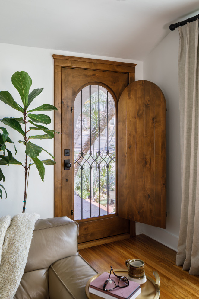 サンディエゴにあるラグジュアリーな地中海スタイルのおしゃれな玄関 (白い壁、無垢フローリング、木目調のドア) の写真