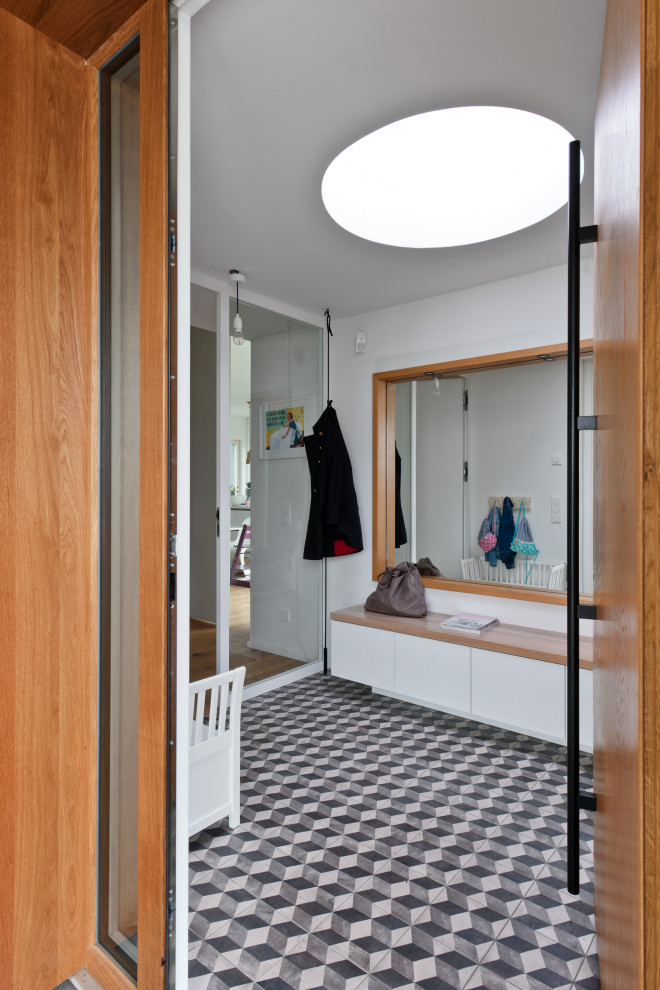 Photo of a mid-sized contemporary foyer in Leipzig with white walls, ceramic floors, a single front door, a medium wood front door, grey floor and wood walls.