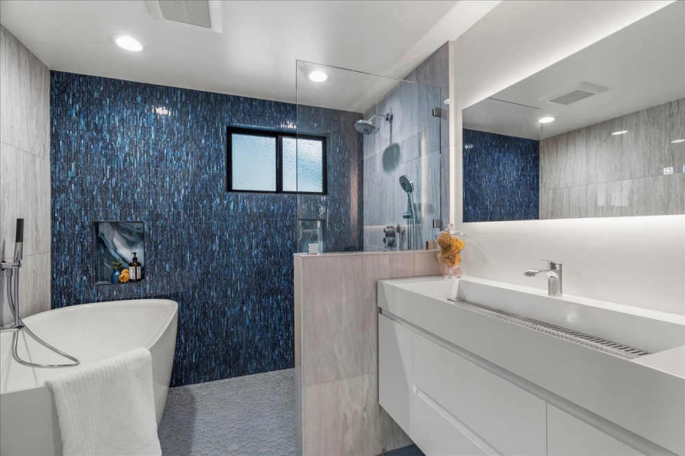 На фото: большая детская ванная комната в морском стиле с плоскими фасадами, белыми фасадами, японской ванной, открытым душем, раздельным унитазом, разноцветной плиткой, плиткой мозаикой, разноцветными стенами, полом из галечной плитки, раковиной с несколькими смесителями, столешницей из искусственного камня, синим полом, открытым душем, белой столешницей, нишей, тумбой под одну раковину и подвесной тумбой