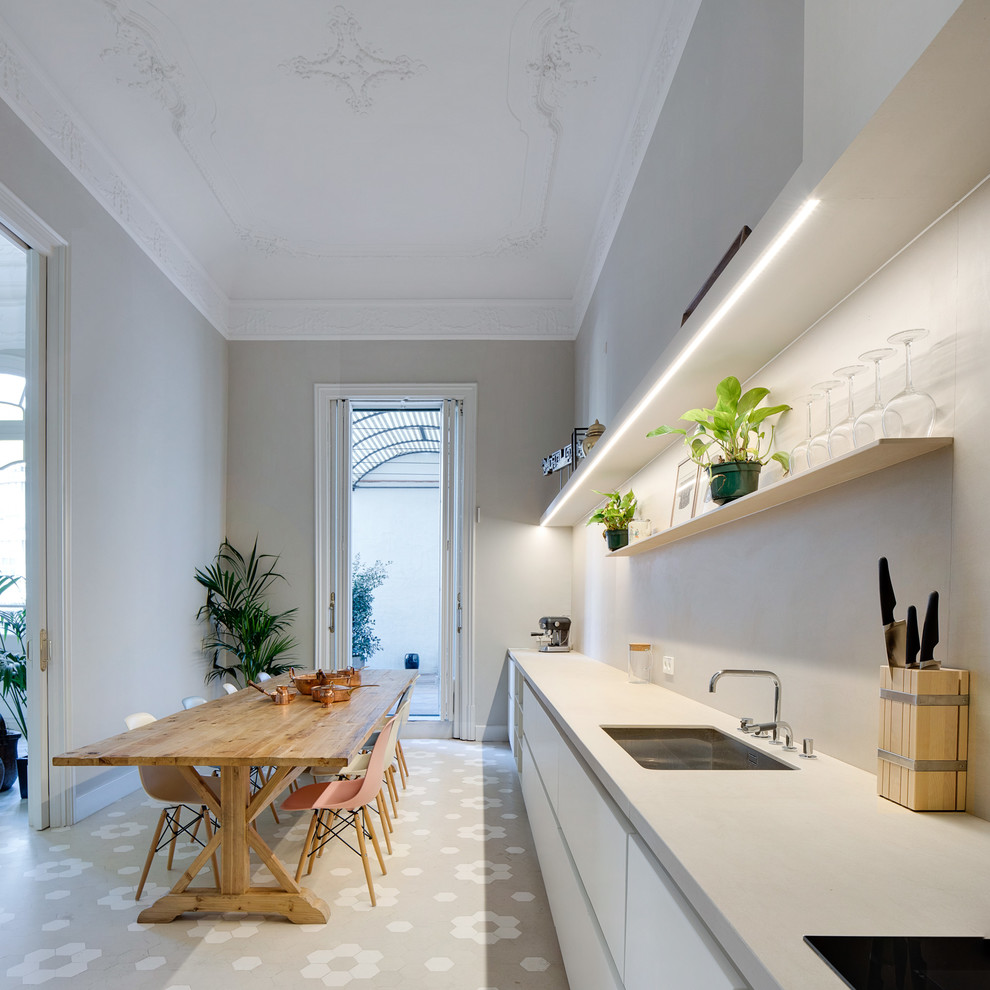Large mediterranean single-wall eat-in kitchen in Barcelona with an undermount sink, flat-panel cabinets, white cabinets, no island, grey benchtop and grey floor.