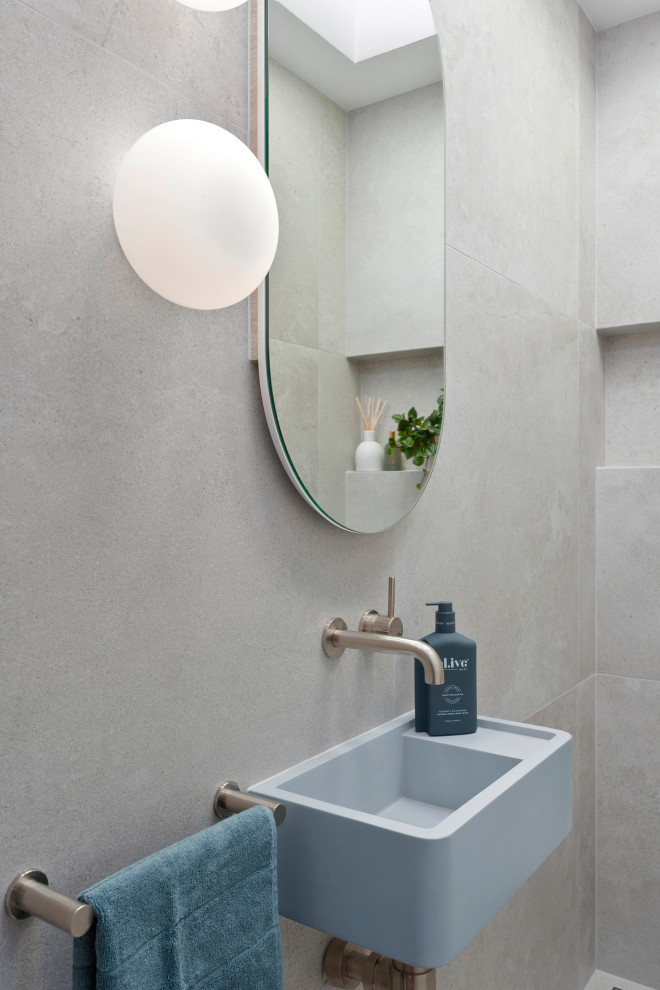 Small contemporary cloakroom in Sydney with blue cabinets, a one-piece toilet, grey tiles, ceramic tiles, grey walls, ceramic flooring, a wall-mounted sink, grey floors and a floating vanity unit.