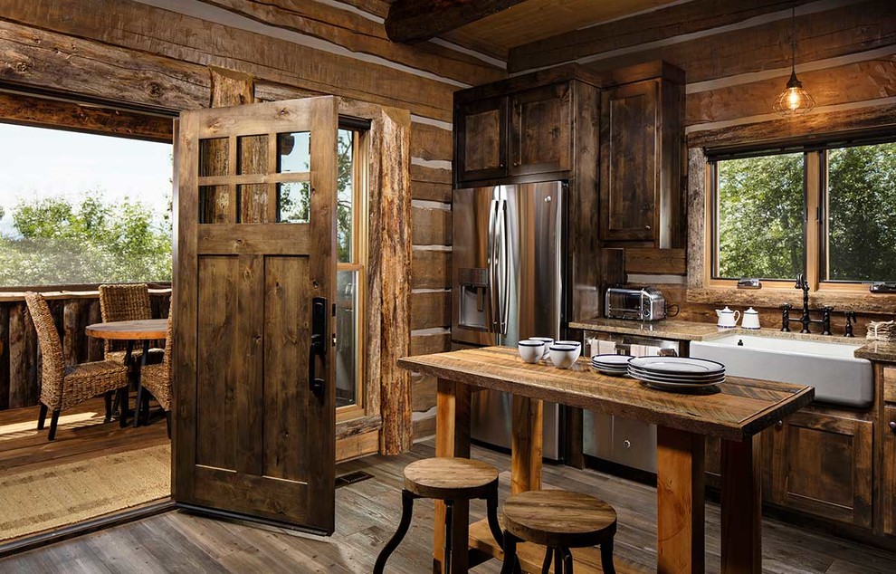 Example of a light wood floor open concept kitchen design with a farmhouse sink, shaker cabinets, dark wood cabinets, marble countertops, wood backsplash, stainless steel appliances, an island and beige countertops