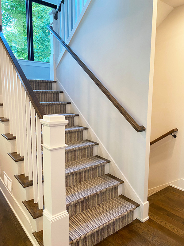 This is an example of a country carpeted straight staircase in Minneapolis with carpet risers and wood railing.