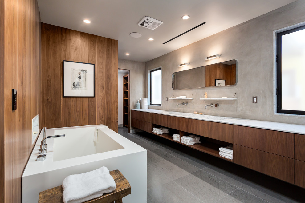 Design ideas for a large contemporary master bathroom in Los Angeles with flat-panel cabinets, dark wood cabinets, a freestanding tub, gray tile, brown walls, a trough sink, grey floor, grey benchtops and porcelain floors.