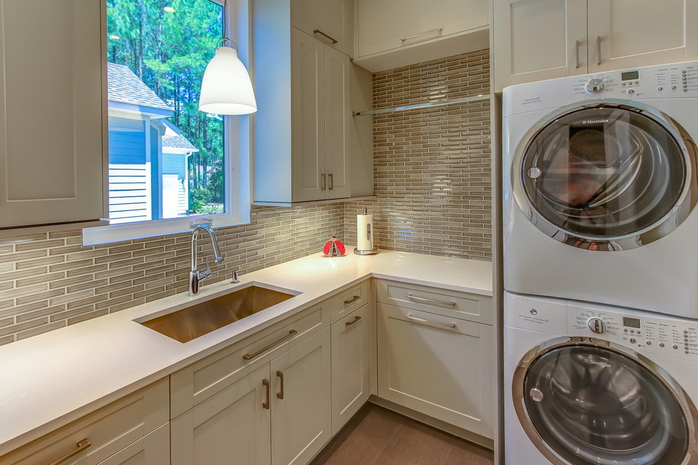 This is an example of a mid-sized contemporary l-shaped dedicated laundry room in Atlanta with a single-bowl sink, porcelain floors, a stacked washer and dryer, shaker cabinets, white cabinets, quartz benchtops and brown floor.