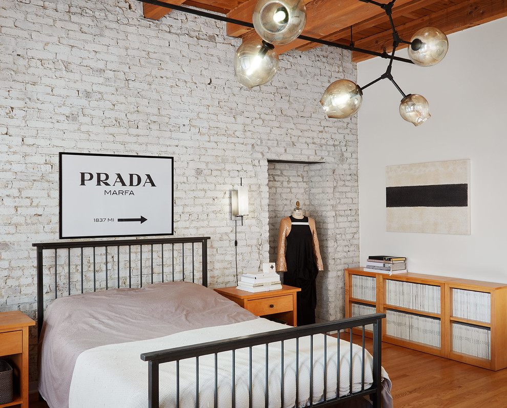 Design ideas for an industrial master bedroom in Chicago with white walls, marble floors and brown floor.