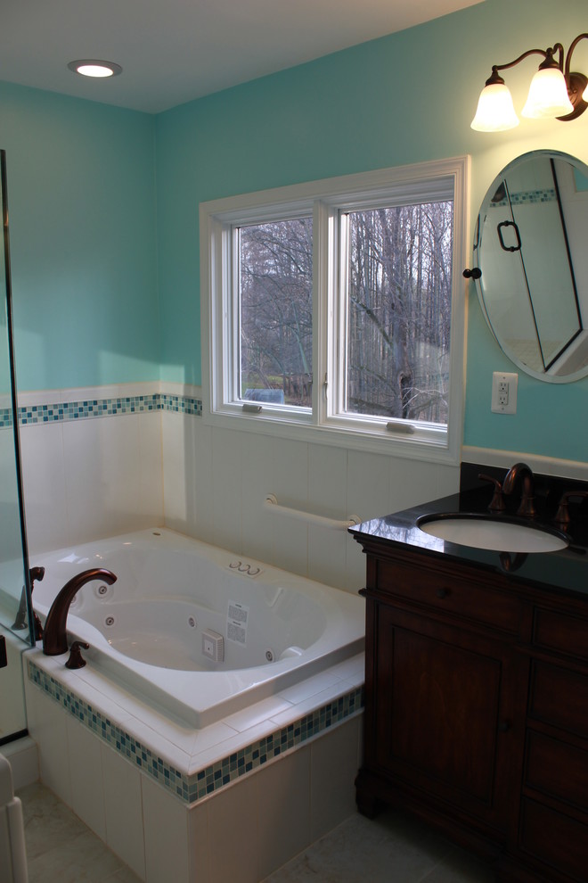 Inspiration for a large transitional white tile and ceramic tile ceramic tile drop-in bathtub remodel in DC Metro with an undermount sink, raised-panel cabinets, dark wood cabinets, granite countertops, a two-piece toilet and blue walls