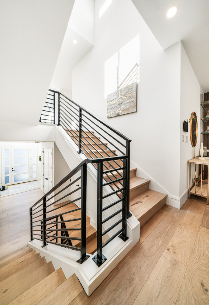 Diseño de escalera en U contemporánea con escalones de madera, contrahuellas de madera y barandilla de metal