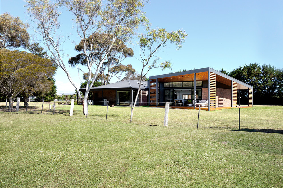 This is an example of a mid-sized contemporary one-storey black house exterior in Geelong with concrete fiberboard siding and a metal roof.