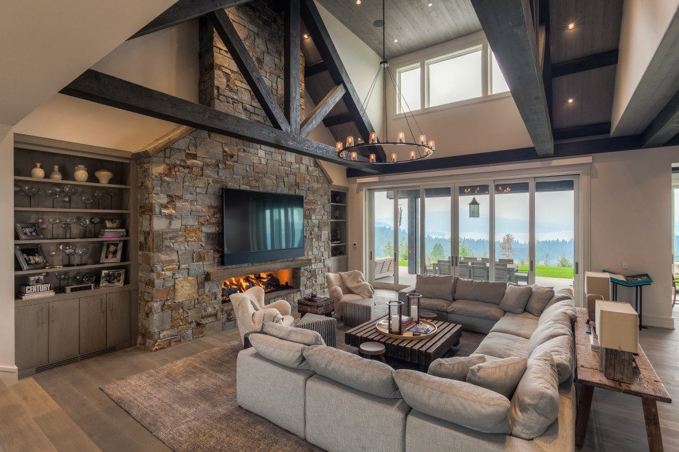 This is an example of a rustic open plan living room in Other with a stone fireplace surround and a wall mounted tv.