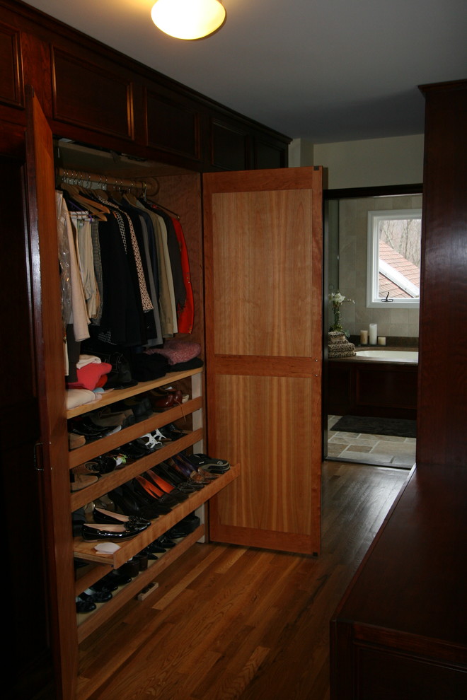 Design ideas for a large traditional gender-neutral built-in wardrobe in New York with medium hardwood floors, recessed-panel cabinets, dark wood cabinets and brown floor.