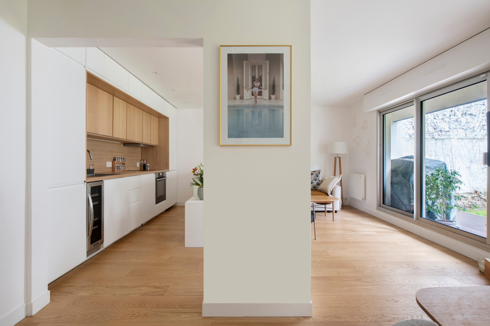 Imagen de sala de estar abierta moderna de tamaño medio sin chimenea con paredes blancas, suelo de madera clara, televisor independiente y suelo beige