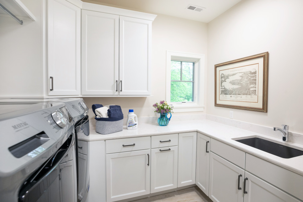 Inspiration for a mid-sized coastal u-shaped porcelain tile dedicated laundry room remodel in Milwaukee with an undermount sink, flat-panel cabinets, white cabinets, quartz countertops, white walls, a side-by-side washer/dryer and white countertops