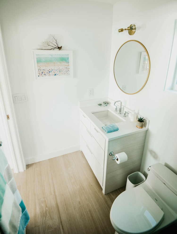 Photo of a small beach style bathroom in Other with flat-panel cabinets, beige cabinets, a one-piece toilet, green tile, glass tile, white walls, porcelain floors, an undermount sink, engineered quartz benchtops, beige floor, an open shower, white benchtops, a single vanity and a freestanding vanity.