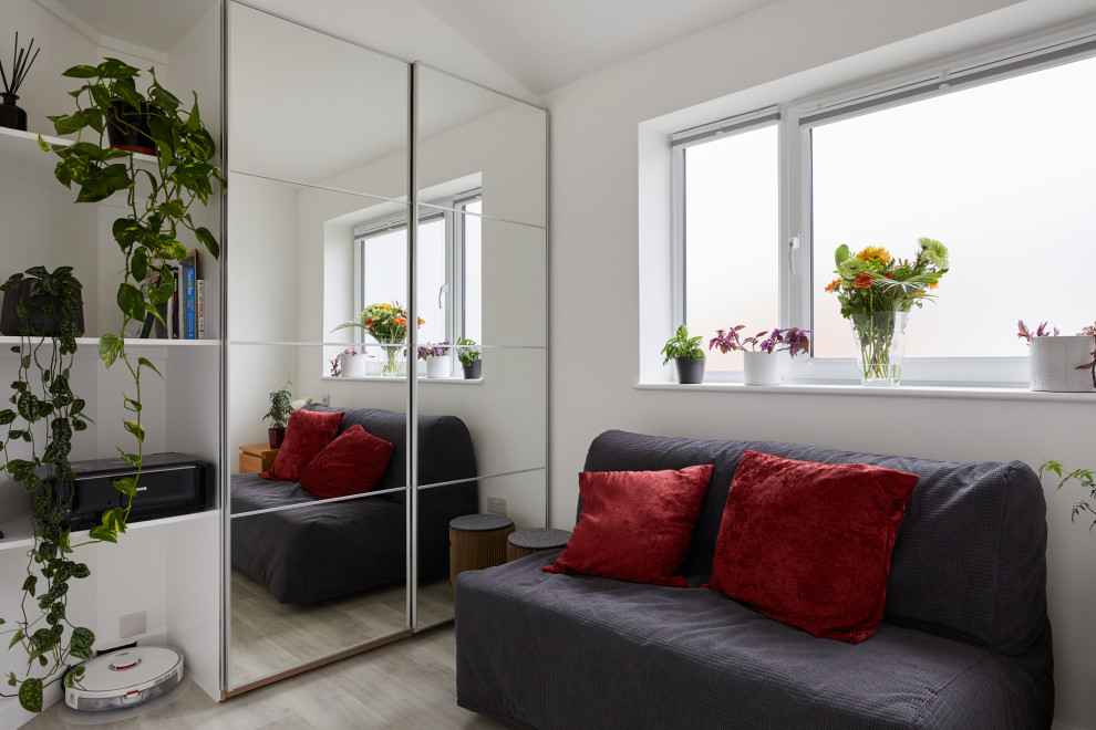 Diseño de habitación de invitados gris y blanca minimalista de tamaño medio con paredes blancas, suelo laminado y suelo gris