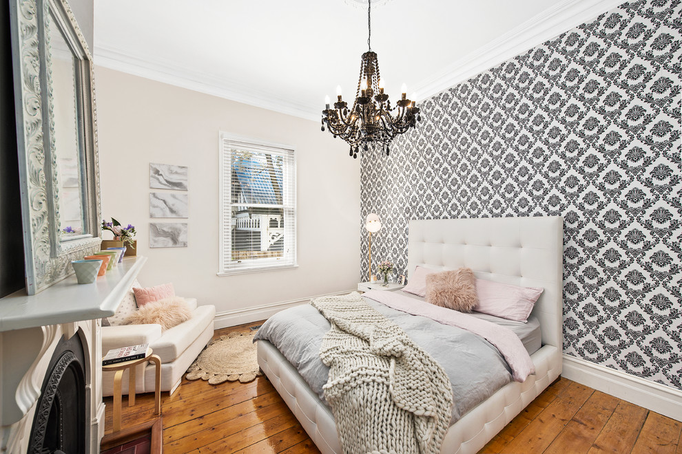 This is an example of a transitional bedroom in Melbourne with multi-coloured walls, light hardwood floors and a standard fireplace.