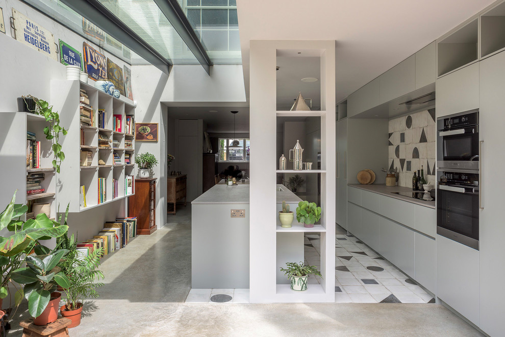 Eclectic kitchen in London with flat-panel cabinets, grey cabinets, solid surface benchtops, ceramic splashback, black appliances, concrete floors, with island, grey floor and grey benchtop.