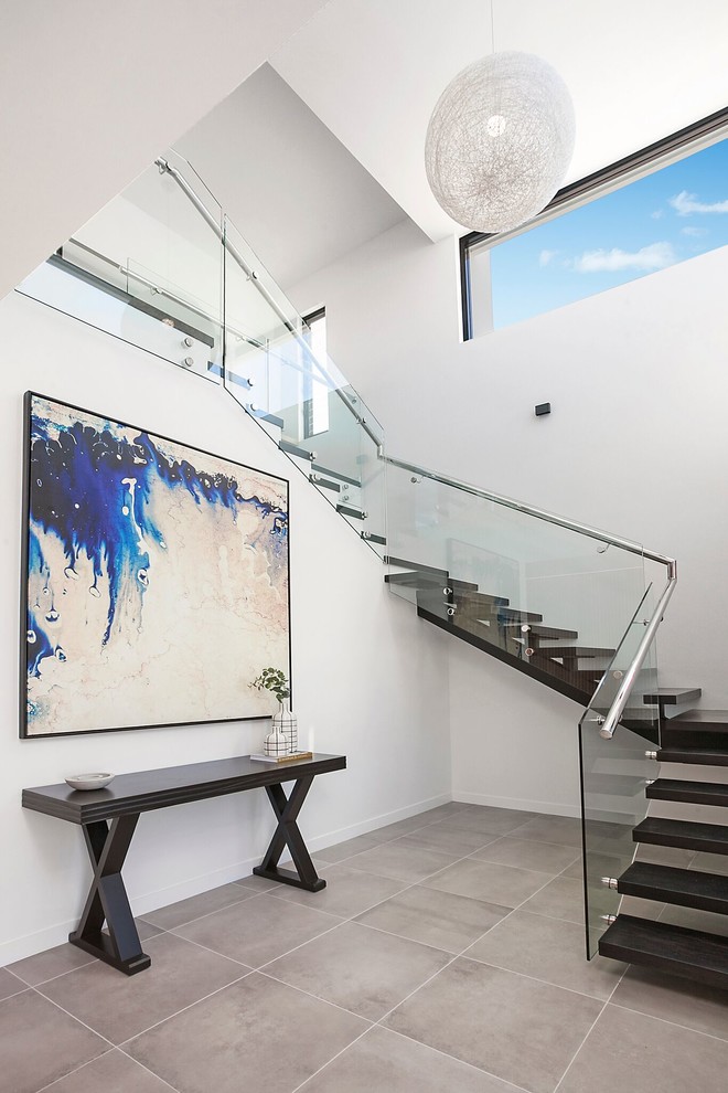 This is an example of a contemporary wood u-shaped staircase in Sydney with glass railing and open risers.