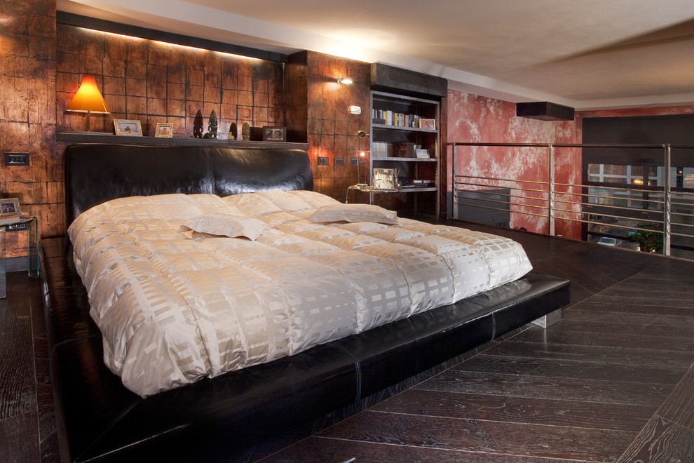 Photo of a large industrial loft-style bedroom in Milan with dark hardwood floors.