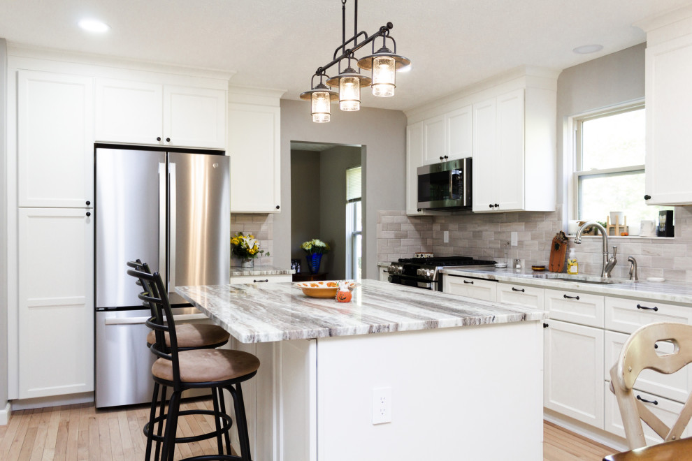 Transitional l-shaped light wood floor and beige floor kitchen photo in Columbus with an undermount sink, white cabinets, gray backsplash, an island and gray countertops
