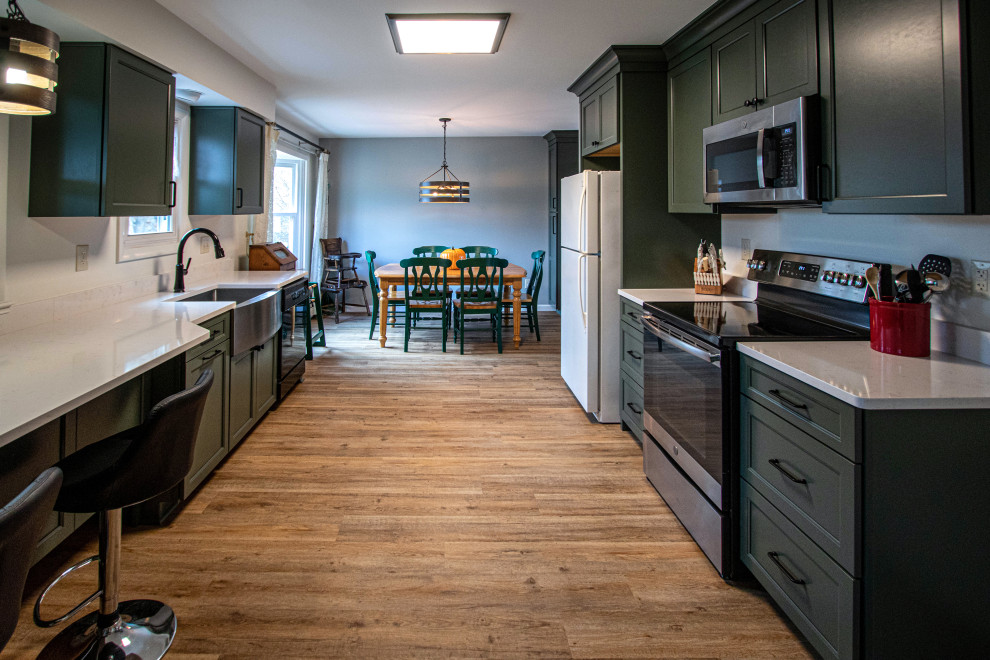 Inspiration for a mid-sized transitional galley eat-in kitchen with an undermount sink, recessed-panel cabinets, green cabinets, quartz benchtops, black appliances, light hardwood floors, no island, brown floor and beige benchtop.