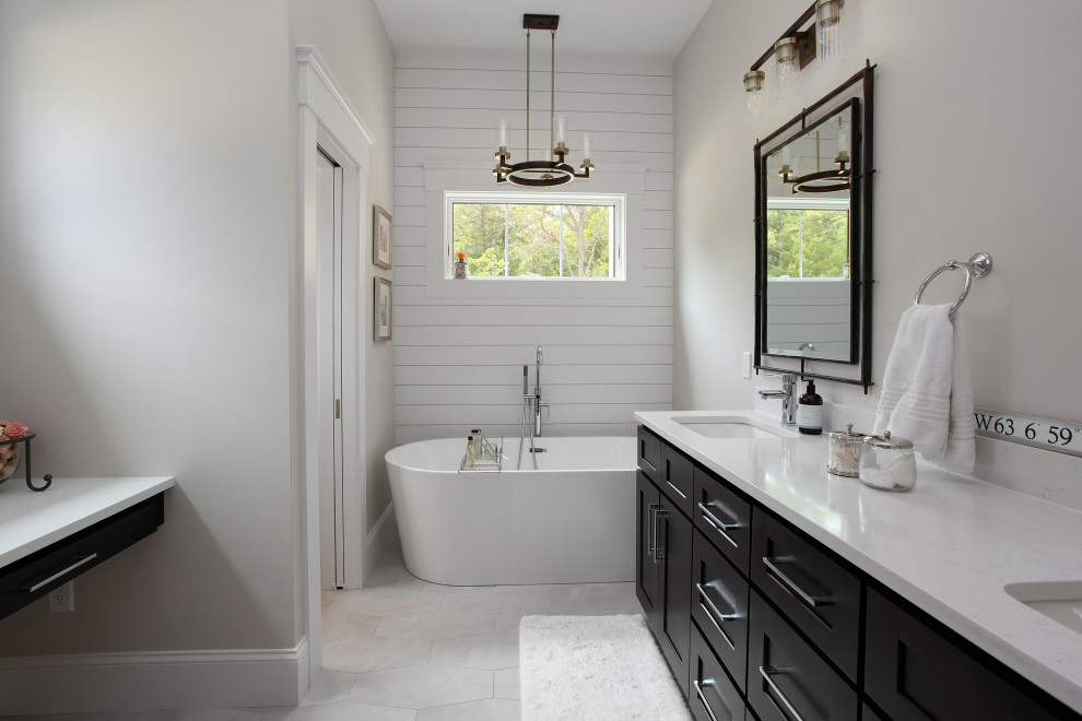 This is an example of a mid-sized country master bathroom in Boston with beaded inset cabinets, black cabinets, a freestanding tub, an alcove shower, white walls, light hardwood floors, engineered quartz benchtops, white benchtops, a double vanity, a built-in vanity, vaulted, a one-piece toilet, a drop-in sink, white floor, an open shower, an enclosed toilet and wood walls.