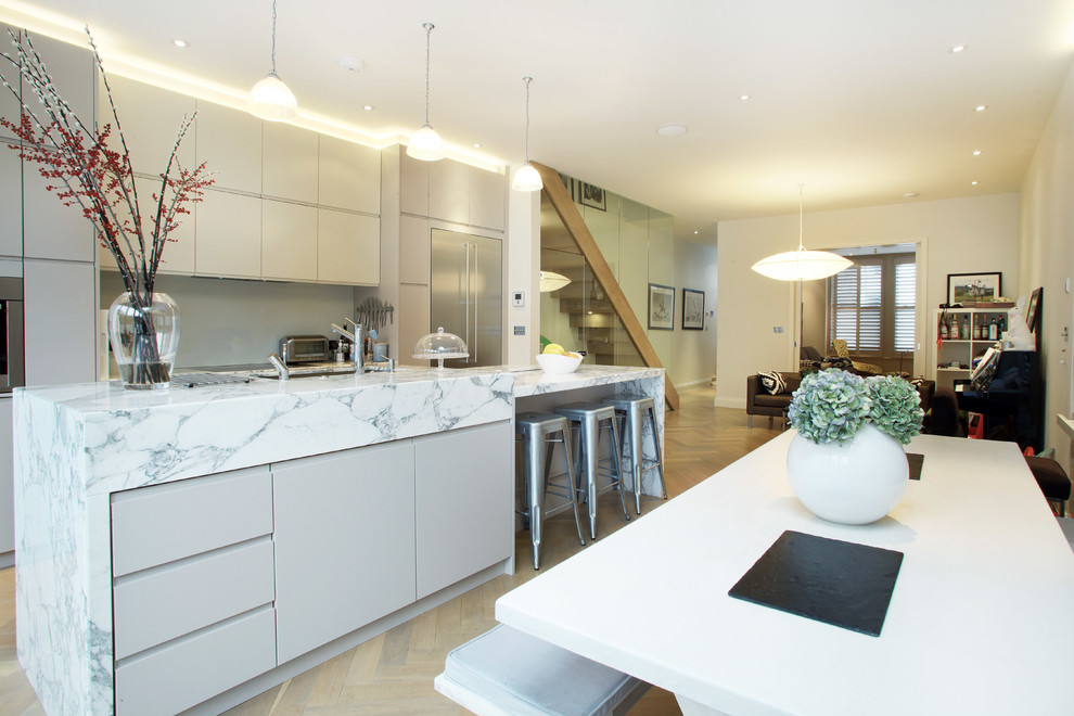 Photo of a contemporary kitchen in London with flat-panel cabinets, white cabinets and stainless steel appliances.