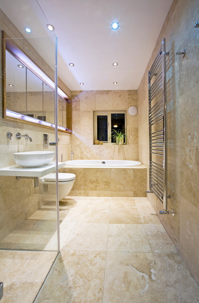 This is an example of a mid-sized contemporary bathroom in Perth with a vessel sink, a drop-in tub, a wall-mount toilet and travertine.