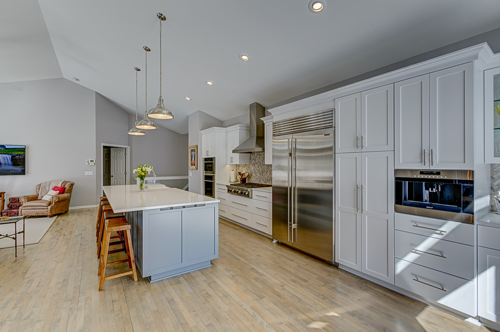 Design ideas for a mid-sized transitional single-wall eat-in kitchen in Minneapolis with a farmhouse sink, shaker cabinets, white cabinets, quartzite benchtops, yellow splashback, stone tile splashback, white appliances, with island and white benchtop.