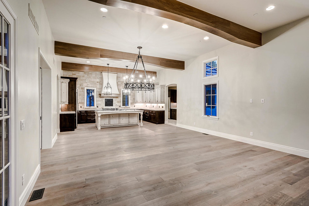 Large u-shaped open plan kitchen in Denver with a farmhouse sink, raised-panel cabinets, distressed cabinets, marble benchtops, white splashback, stone tile splashback, stainless steel appliances, light hardwood floors, with island, brown floor and white benchtop.